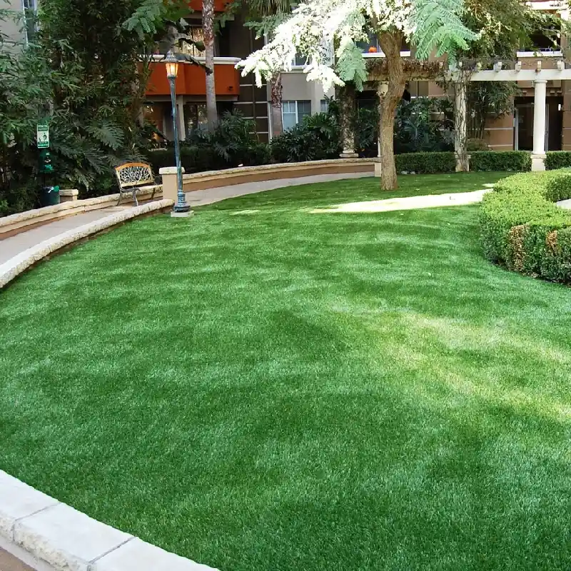 bright green artificial grass lawn in a manicured courtyard, surrounded by a low curved stone wall