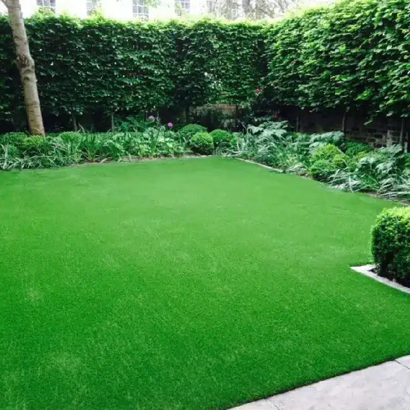uniform, bright green artificial grass lawn is installed in a backyard