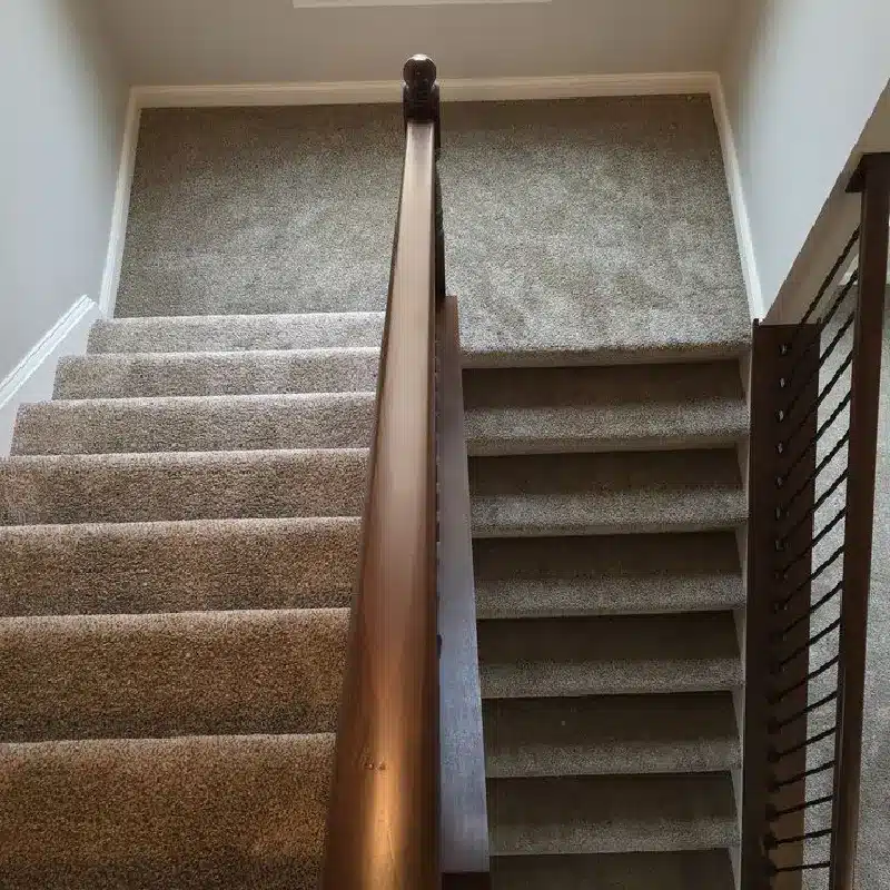 Top-down view of a staircase carpeted in a light brown